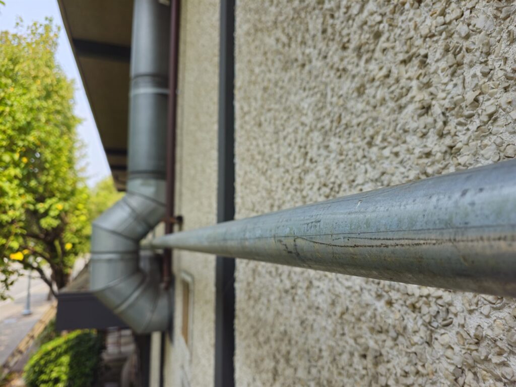 Newly run galvanized gas supply line mounted along a stucco building exterior