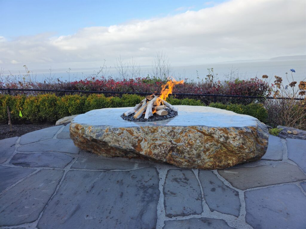 Natural granite boulder carved into a gas fire feature on a flagstone patio overlooking Puget Sound