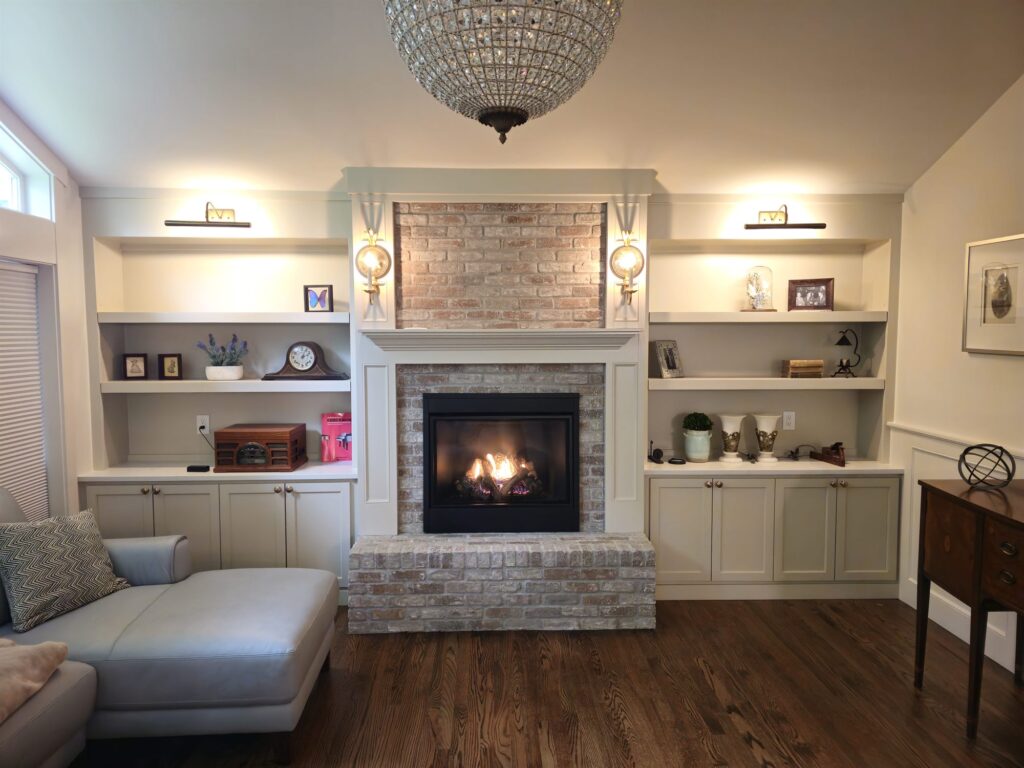 Gas fireplace in a whitewashed brick surround with a raised hearth between white built-in shelves