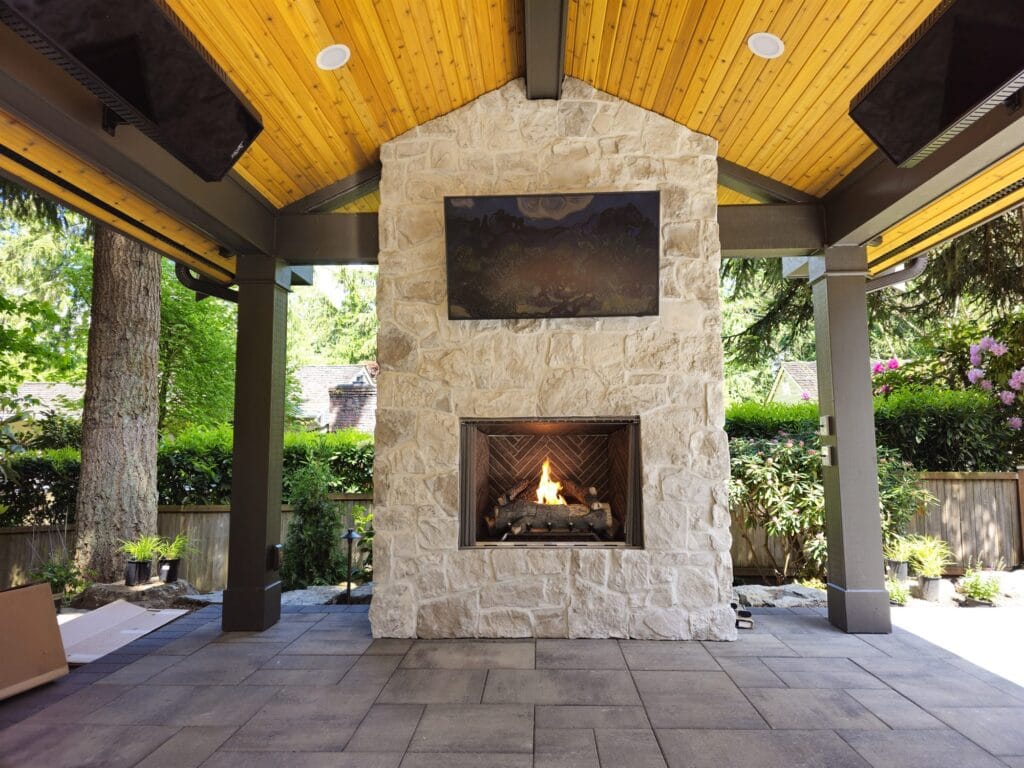 Outdoor gas fireplace in a light stone chimney under a cedar-ceiling covered patio
